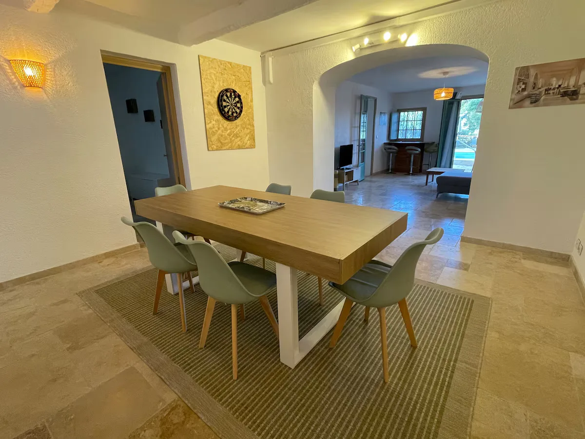 Salle à manger disposant d'une table pour 6 personnes et d'une cible de fléchettes